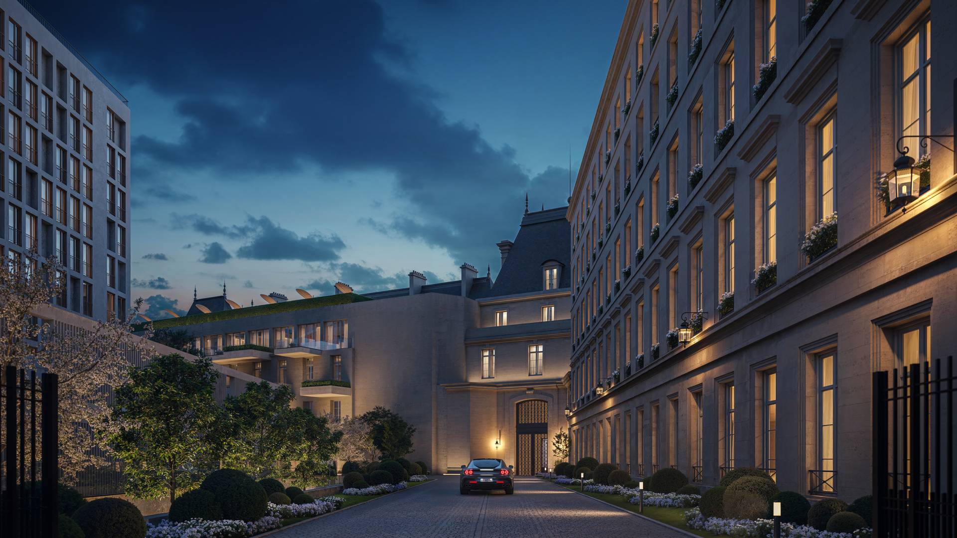 Elegant hotel driveway at dusk with landscaped gardens, lit windows, and a car approaching a grand historic entrance.