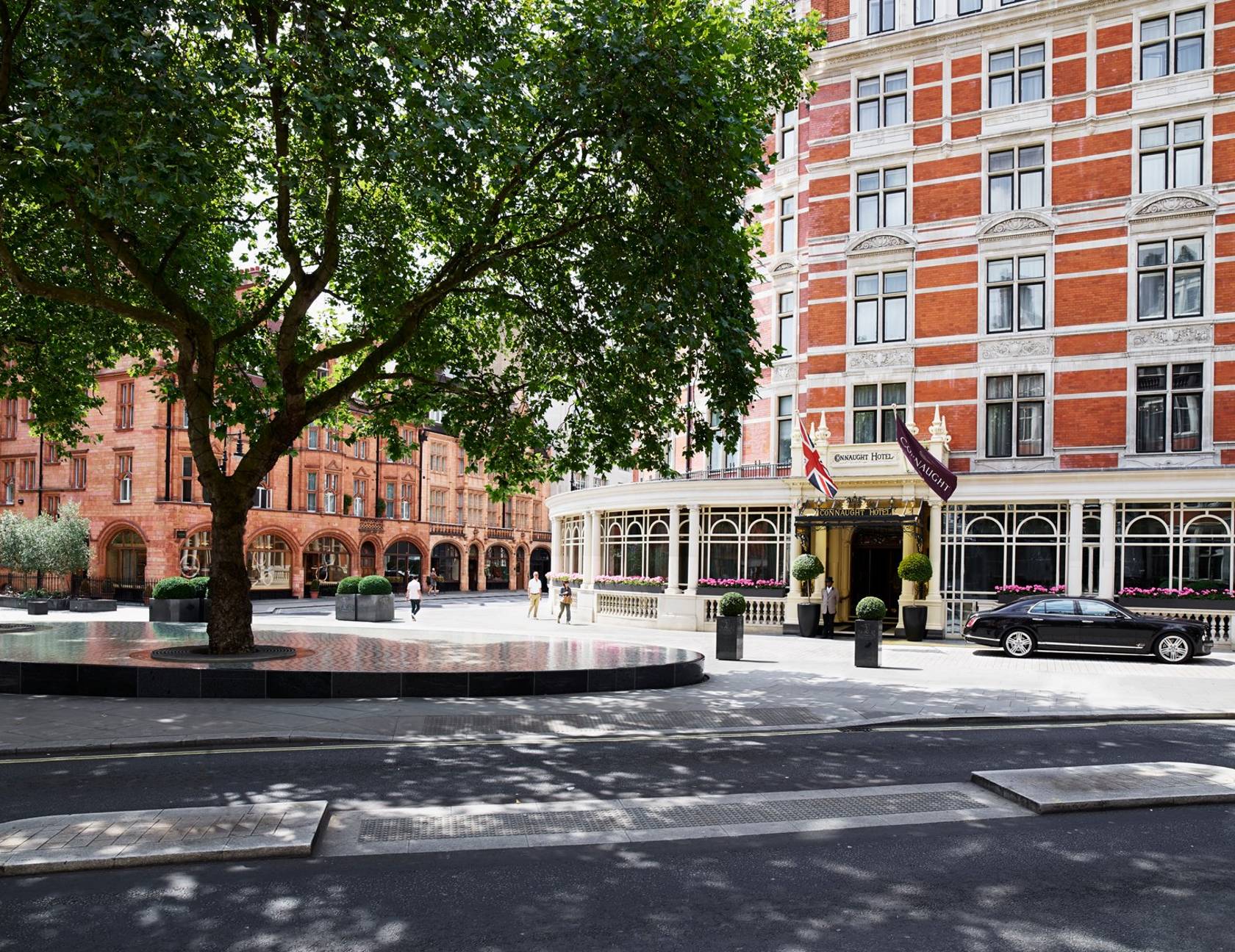The exterior of The Connaught Hotel in Mayfair, with a grand entrance, Union Jack flag, and elegant red-brick facade.