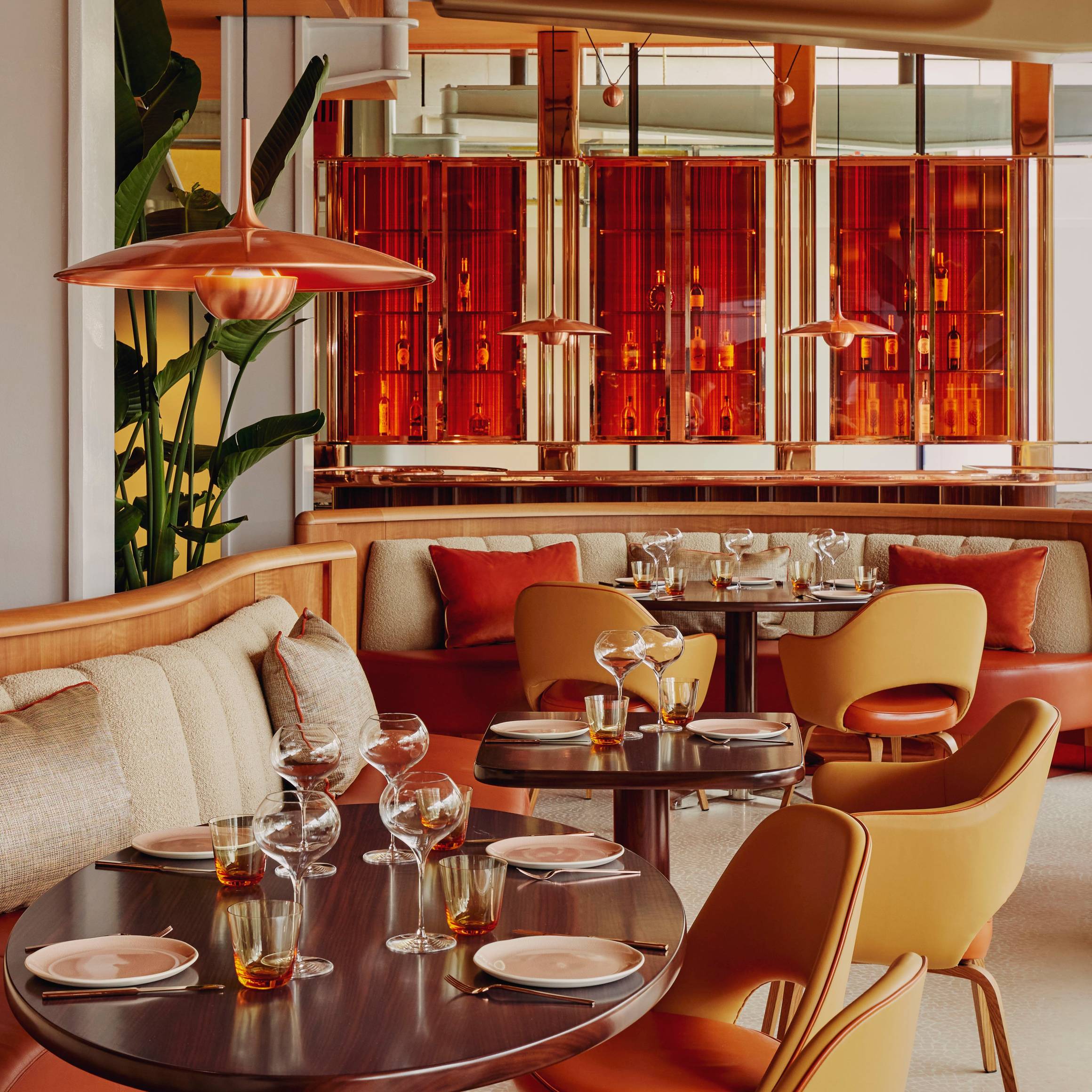 Contemporary dining space with warm tones, curved seating, stylish pendant lights, and vibrant red accents creating a modern ambiance.