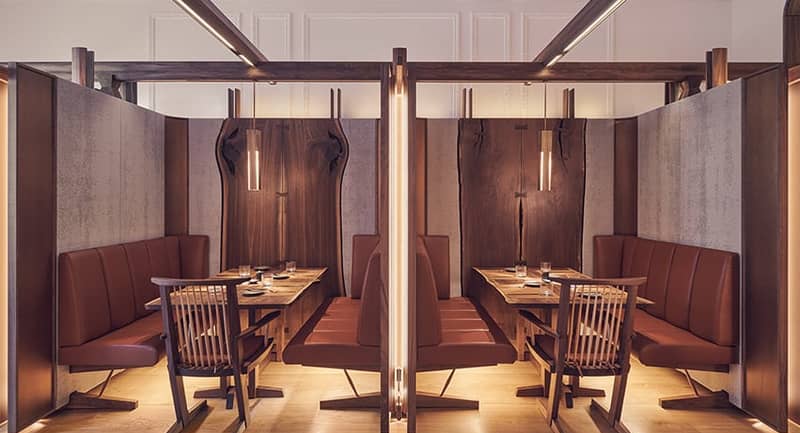 A sophisticated dining space with intimate wooden booths, leather seating, and warm ambient lighting.