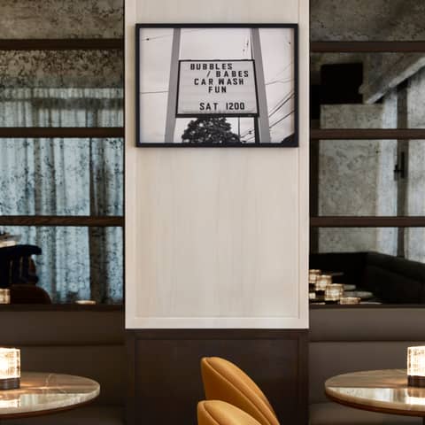 Modern bar area with burnt-orange chairs, marble tabletops, and a vintage-inspired monochrome photograph for a playful touch
