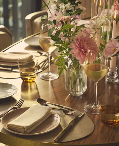 Elegant table setting with fresh flowers, candlelight, and glassware; intimate private dining room with warm lighting and plush seating.