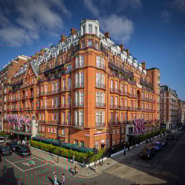 The grand red-brick facade of Claridge’s Hotel in Mayfair, adorned with Union Jack flags and intricate architectural details.