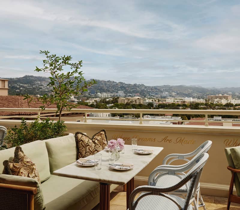 Charming rooftop terrace featuring cozy seating, marble tables, floral accents, and expansive views of the cityscape