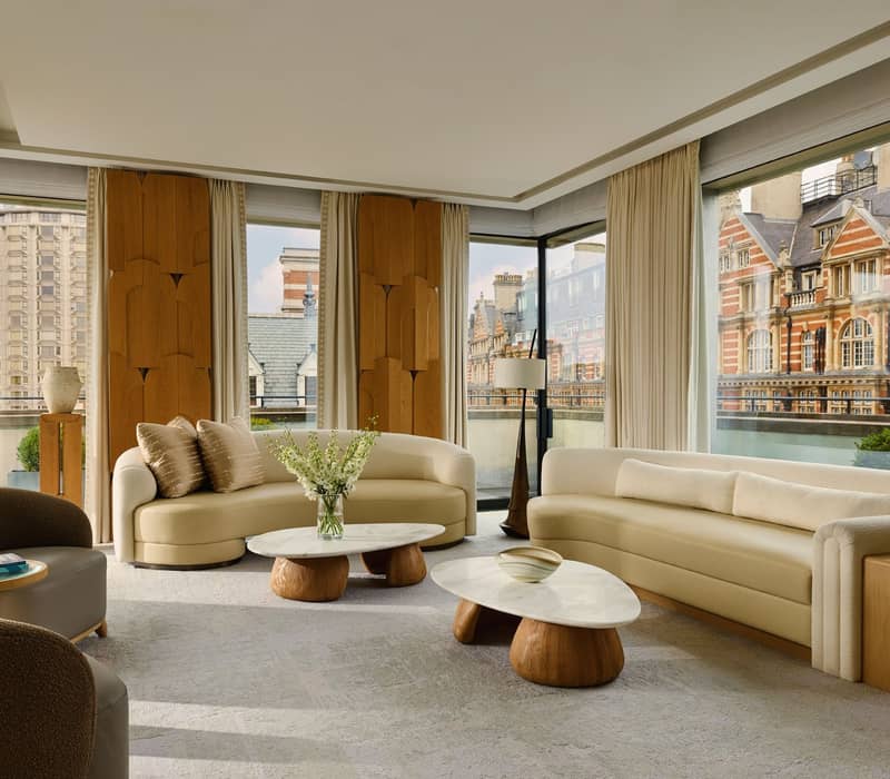 A serene, light-filled space with sculptural furnishings, floor-to-ceiling windows, and panoramic views of historic Knightsbridge architecture.