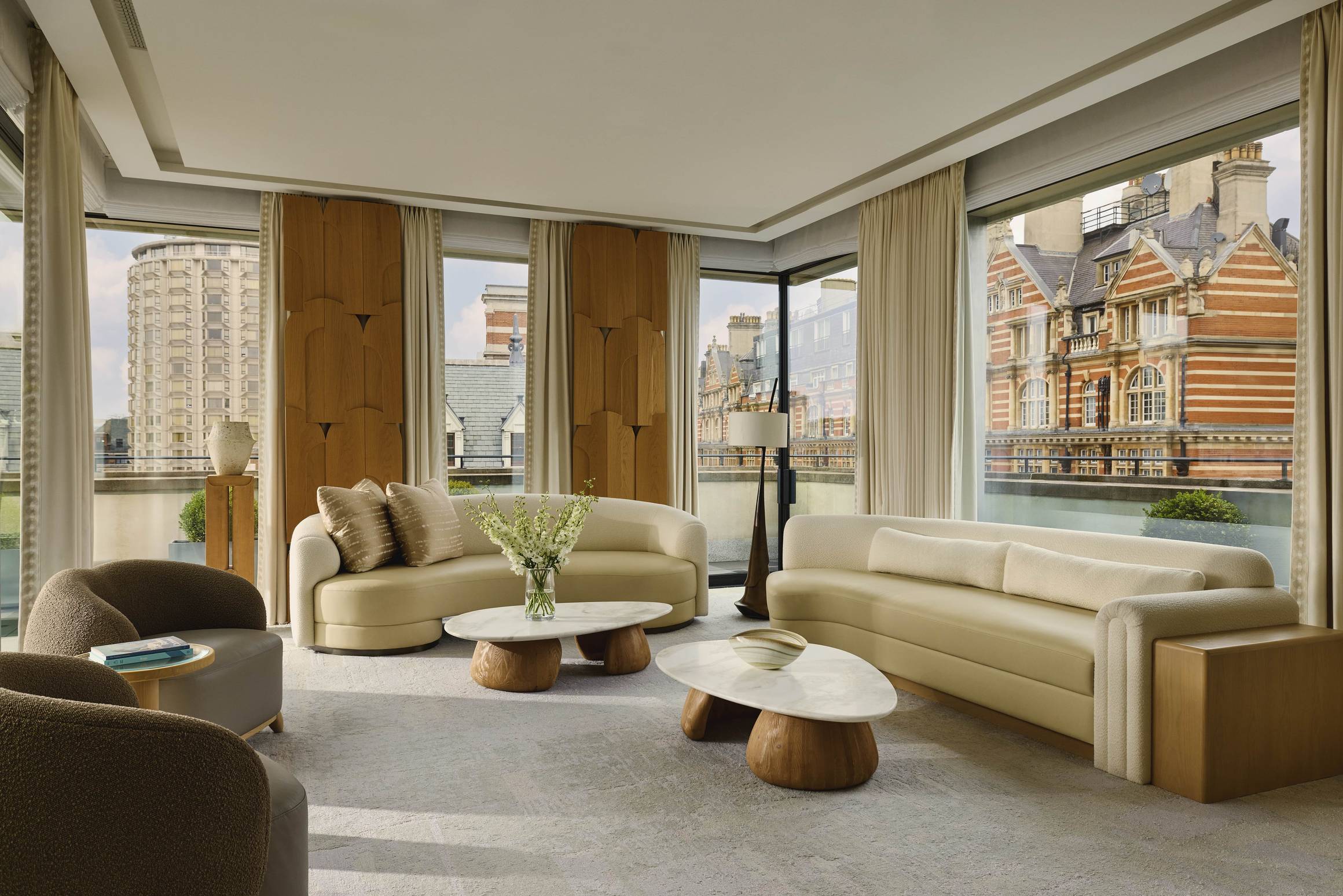Spacious living room with modern furnishings and panoramic city views through floor-to-ceiling windows.