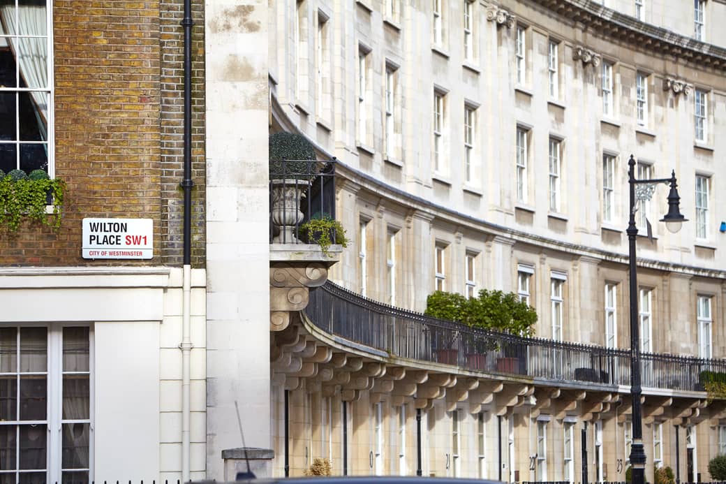 Wilton Place SW1 street sign with elegant Georgian architecture, wrought-iron railings, and classic Westminster charm in the background.