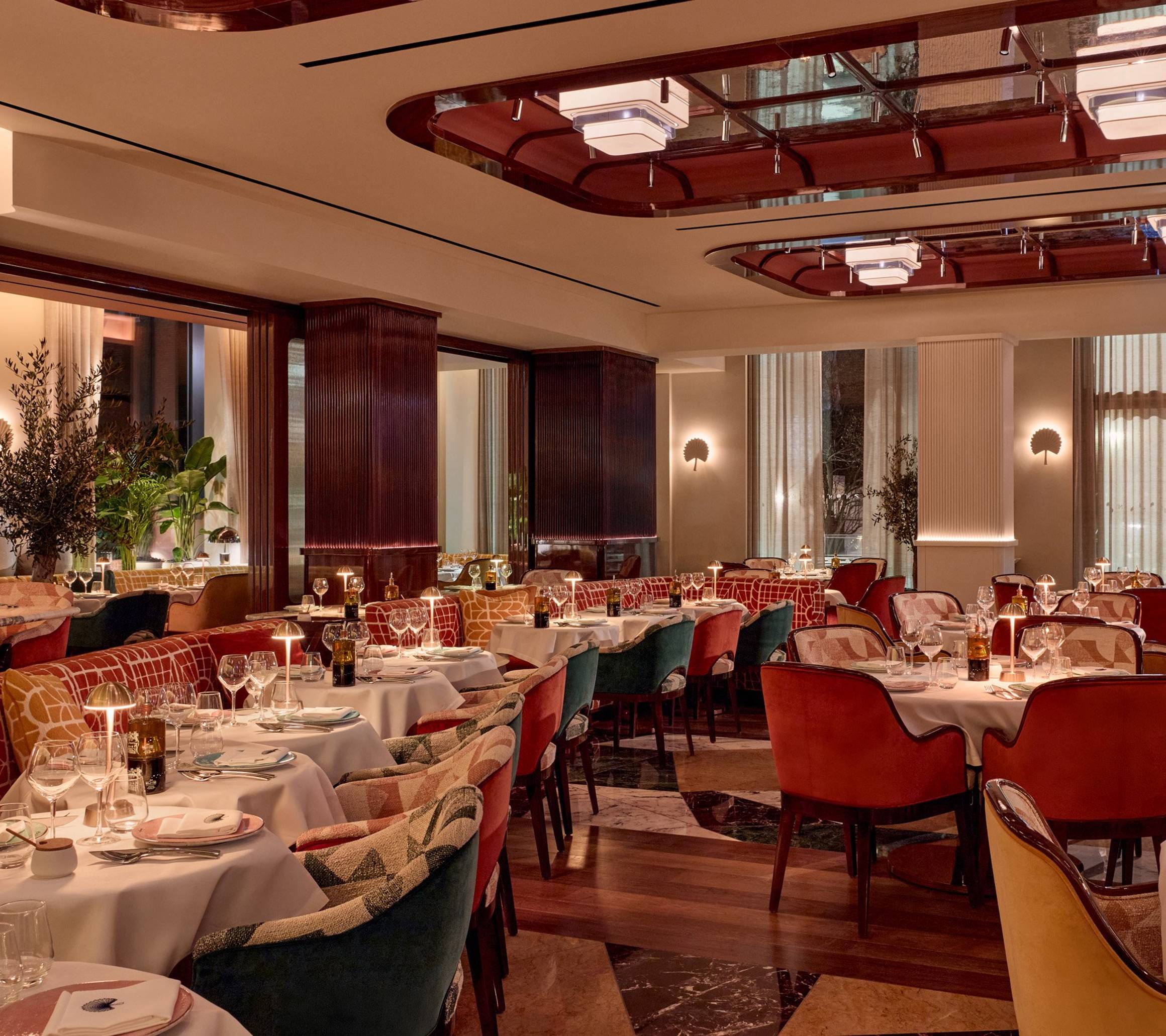 Elegant restaurant interior with rich tones, plush seating, soft lighting, and art deco-inspired details throughout the dining space.