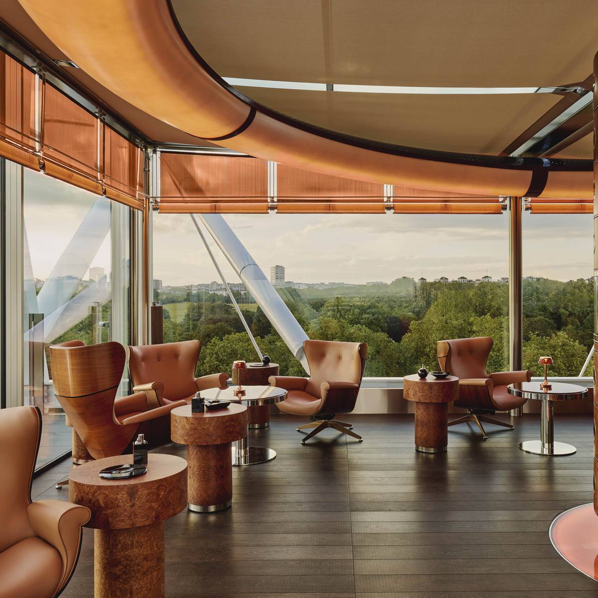 Luxurious cigar lounge with leather armchairs, bespoke decor, and panoramic views of lush greenery through floor-to-ceiling windows