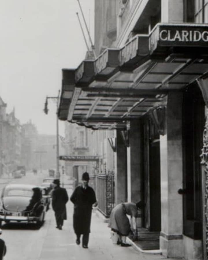 Historic black-and-white photo of Claridge’s Hotel entrance, London, capturing a classic scene with vintage cars and pedestrians
