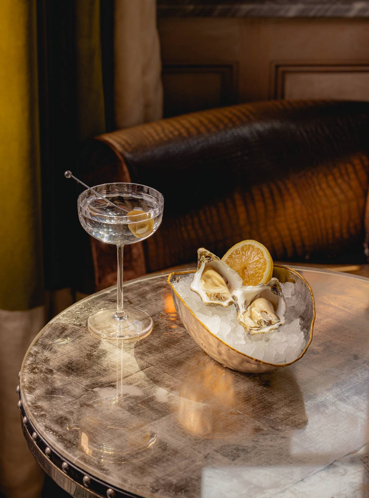 A classic martini served alongside a luxurious presentation of fresh oysters on ice with a lemon wedge
