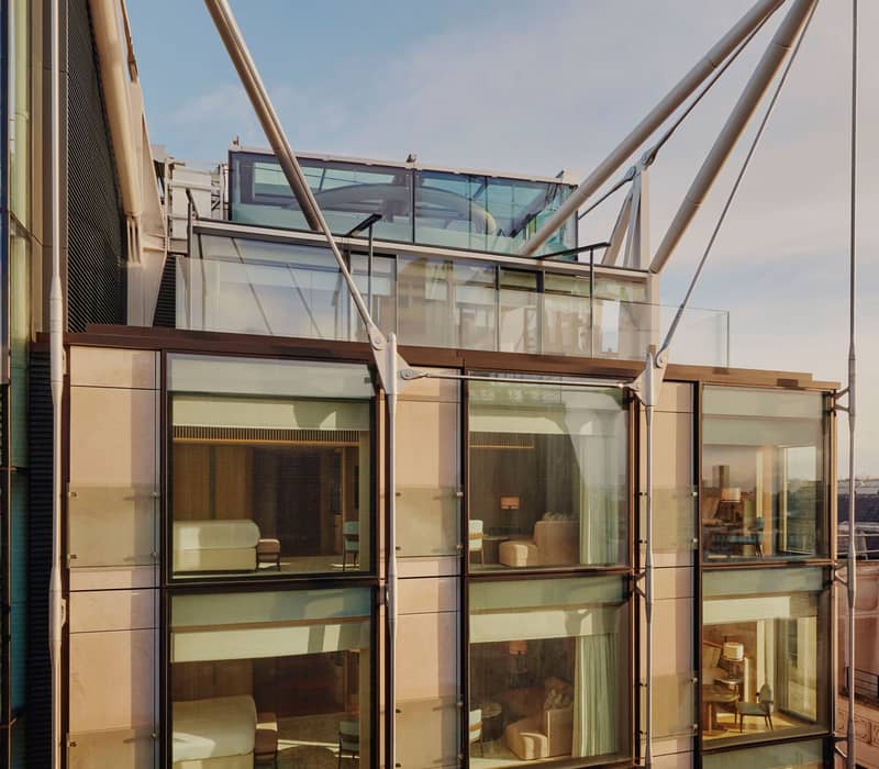 The Emory's modern facade showcases floor-to-ceiling windows, reflecting bespoke interiors and architectural harmony under its striking steel frame.