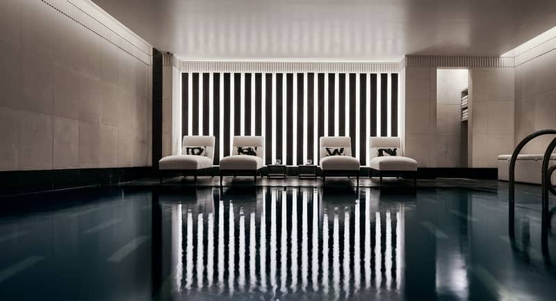 A serene indoor pool retreat with minimalist design, plush loungers, and ambient lighting, offering pure relaxation and tranquility.