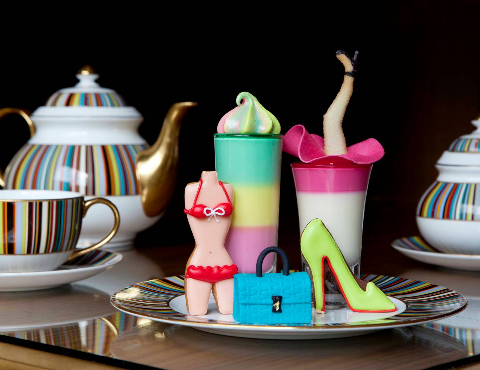 A whimsical fashion-inspired afternoon tea featuring couture-themed pastries, vibrant desserts, and elegant striped china, celebrating style with a playful indulgence.