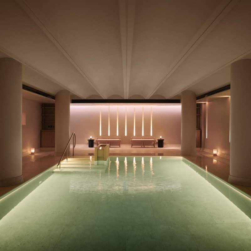 A serene indoor spa pool surrounded by soft lighting, minimalist design, and cozy seating for ultimate relaxation.