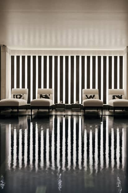 Elegant spa pool area featuring plush lounge chairs, soft lighting, and vertical wood accents, evoking a serene atmosphere