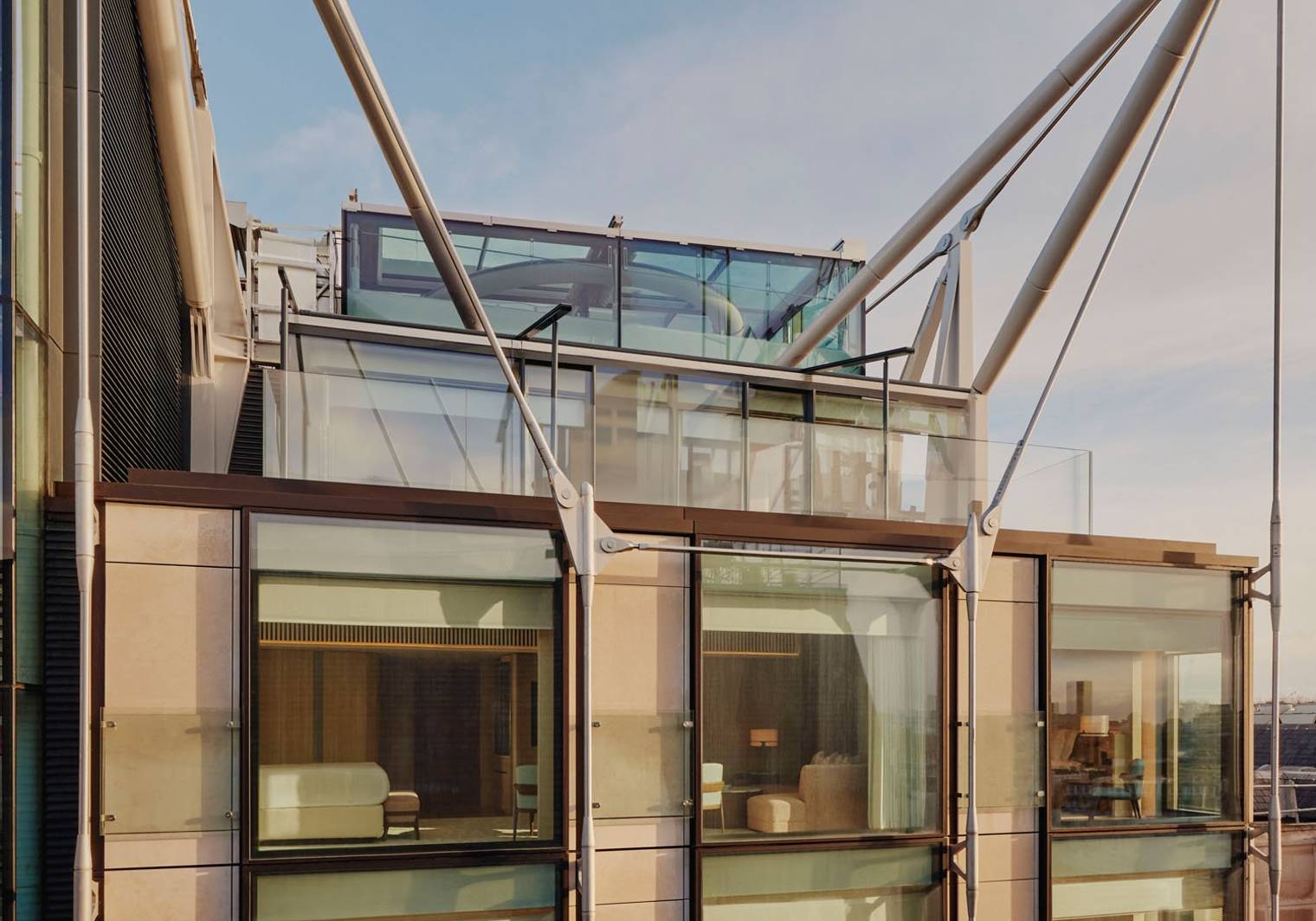 Exterior of The Emory, showcasing modern glass facade, elegant interiors, and striking architectural supports under a clear blue sky