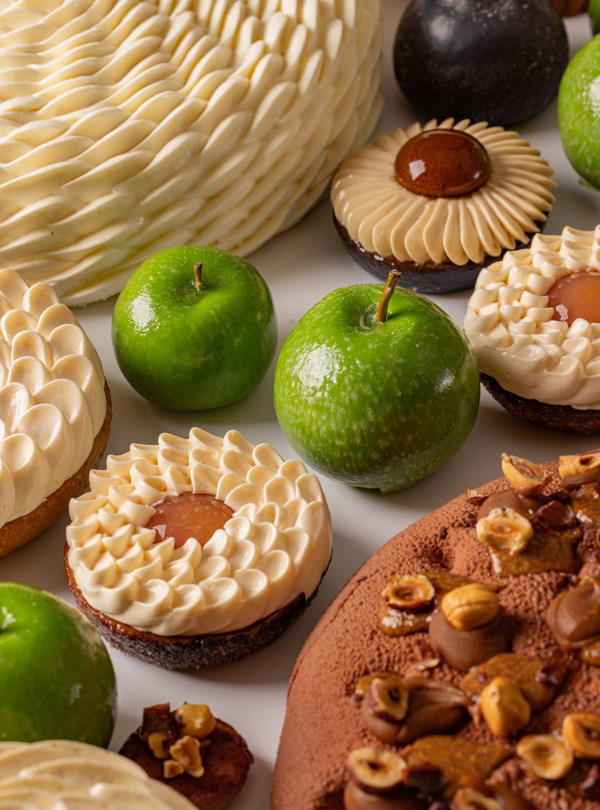 A delectable assortment of gourmet desserts featuring intricate pastries, chocolate confections, and fresh green apples as accents.