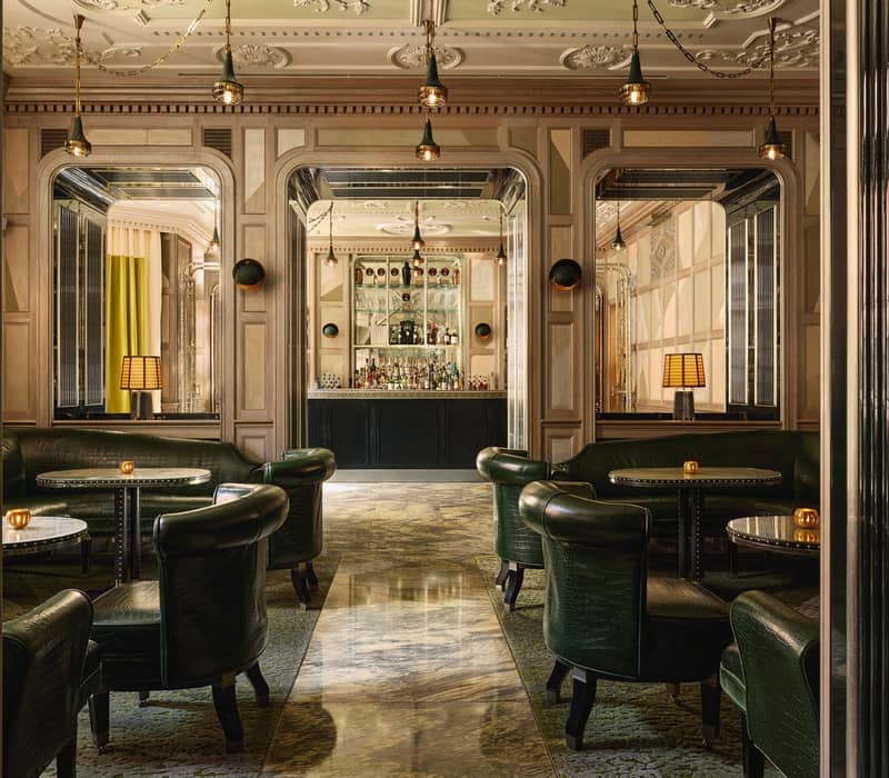 Opulent bar with mirrored accents, crocodile-patterned leather seating, marble flooring, and a sleek counter framed by luxurious decor.