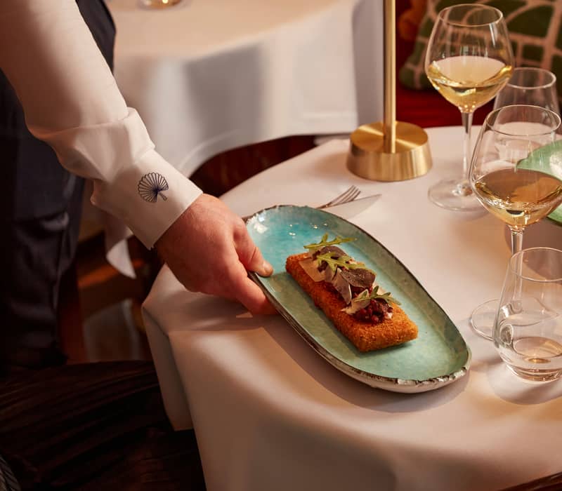 a delicate dish presented on an artisanal plate, paired with fine wine, in an elegant dining setting.