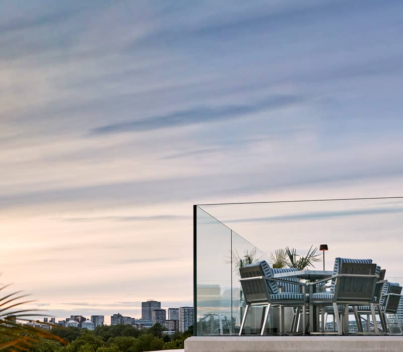 A tranquil rooftop terrace with elegant seating, overlooking the city skyline and lush greenery, bathed in the soft hues of dusk.
