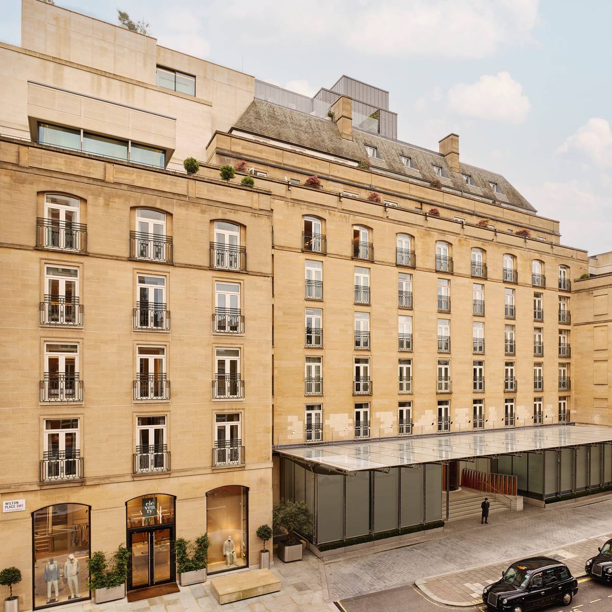 The Berkeley's stately exterior, featuring classic stone architecture, wrought-iron balconies, and a sophisticated entrance with glass canopies in Knightsbridge.