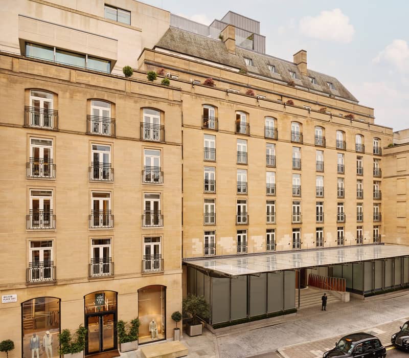 The Berkeley's stately exterior, featuring classic stone architecture, wrought-iron balconies, and a sophisticated entrance with glass canopies in Knightsbridge.