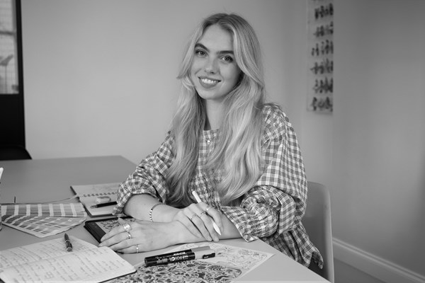 Black and white portrait of martha with her sketch pens and books infront of her on a table