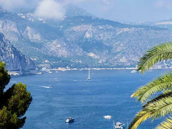 The gorgeous azure waters of the French Riviera with a  boat sailing in front of a rocky hillside