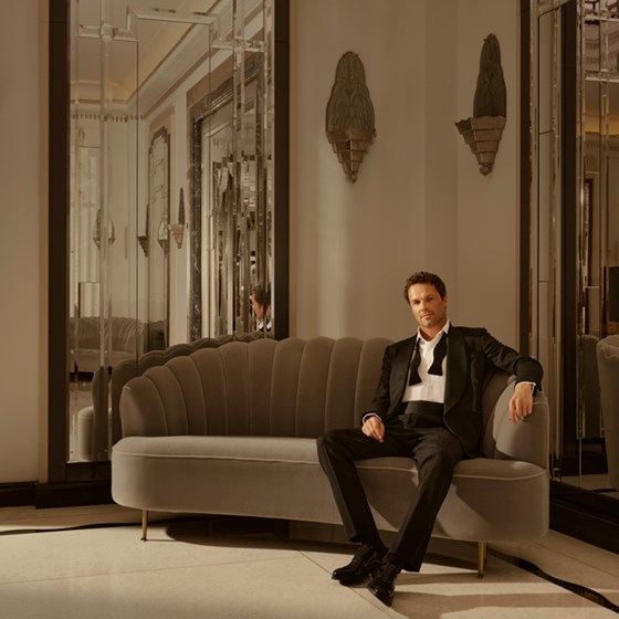 Man wearing a tuxedo and sitting on a sofa in Claridge's Ballroom