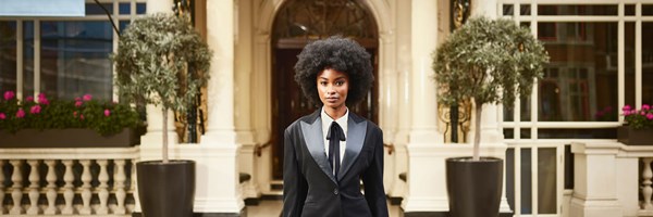 A lady dressed in a smart suit stands in front of the Connaught