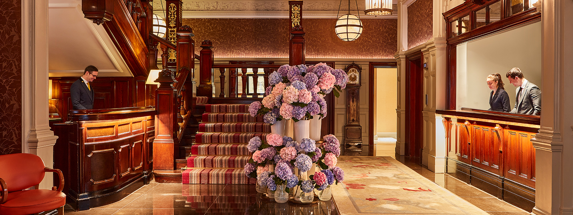 The Connaught Lobby - view of the famous wood staircase with flowers and reception desks on the sides.