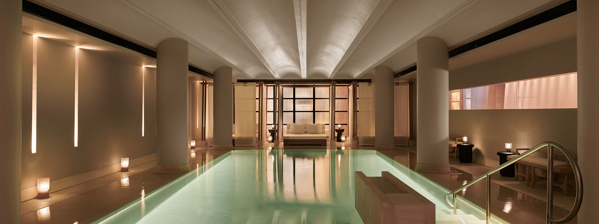 Swimming pool with white cabanas and candles around the side in spa