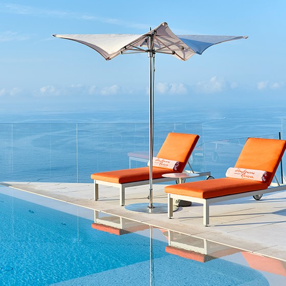 Pool and loungers at the Maybourne Riviera, with view over the sea.