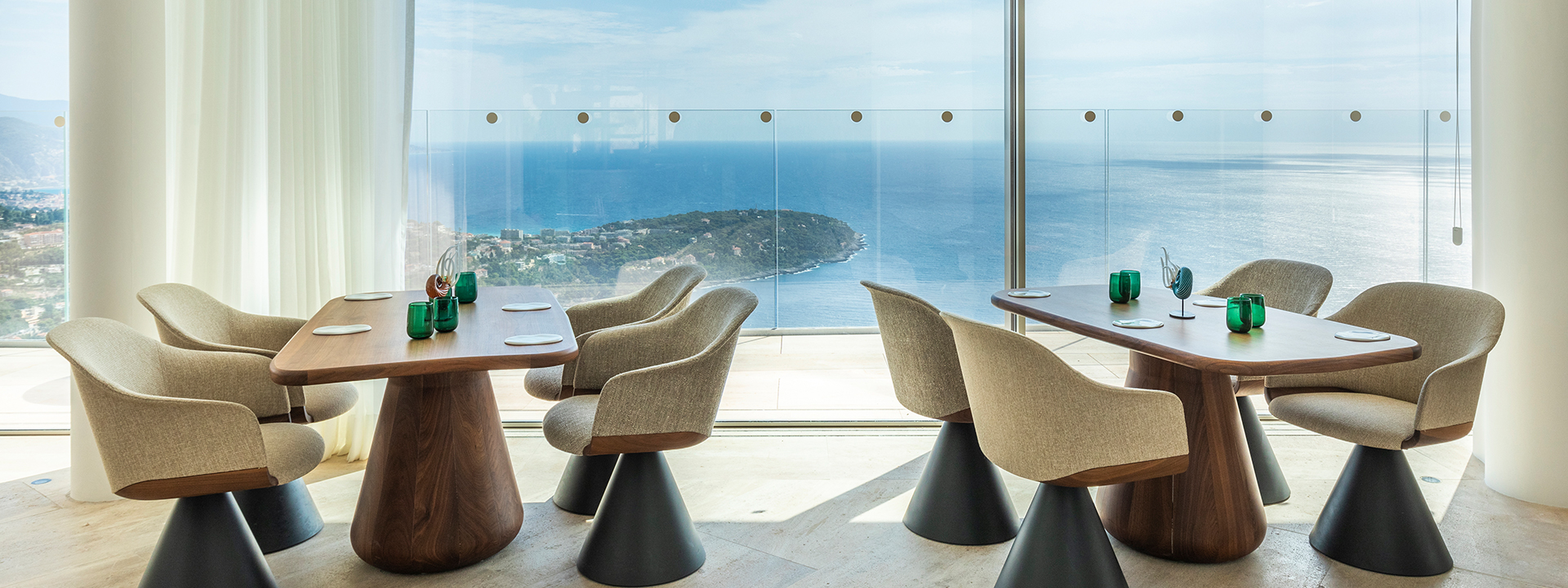 Ceto restaurant at The Maybourbe Riviera - two tables set up in front of the floor to ceiling windows with views onto the sea.