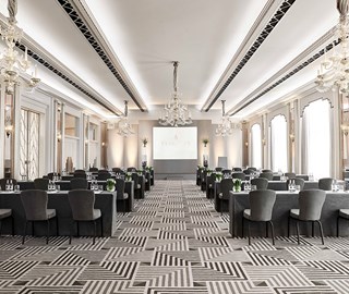 Ballroom at Claridges - reception room with grey chairs and tables lined up and a screen at the back of the room.